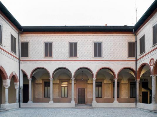 cortile interno edificio medievale bianco con porticato coperto e finestre alte e strette